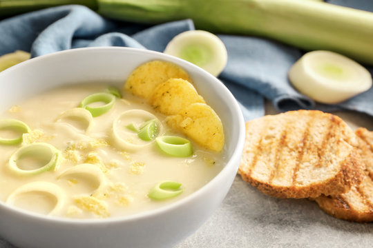 Bowl of yummy potato soup with leek and croutons on table