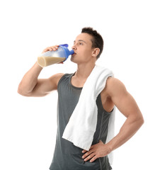 Handsome young man drinking protein shake on white background