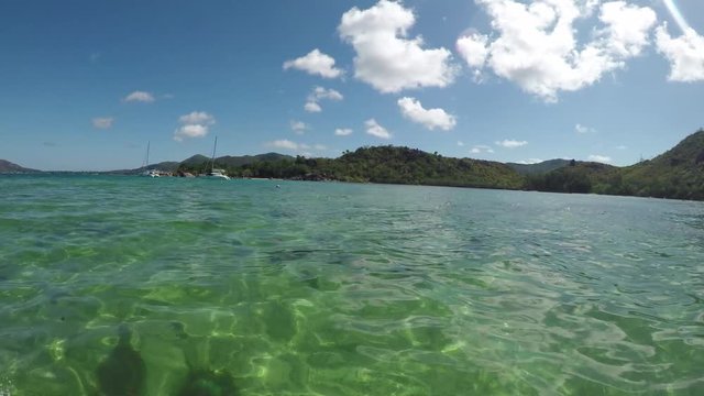 GoPro point of view from the side of a speedboat during a boat ride, approaching an island in the Seychelles with water splashing. POV.  