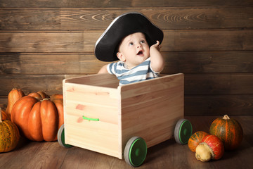 Adorable baby in pirate costume near wooden wall. Halloween concept