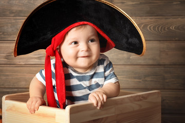 Adorable baby in pirate costume on wooden background. Halloween concept