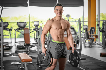 Fototapeta na wymiar Muscular man with barbell plates in gym