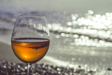 Glass of wine on sand on sea background.