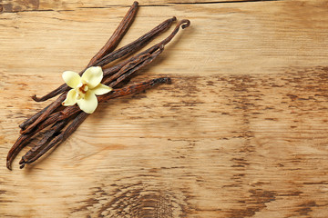 Dried vanilla pods and flower on wooden background