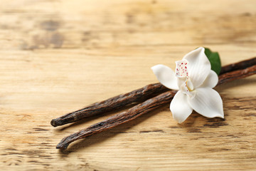 Dried vanilla pods and flower on wooden background