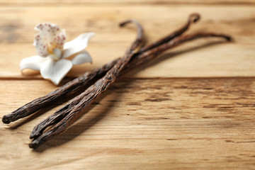 Dried vanilla pods and flower on wooden background