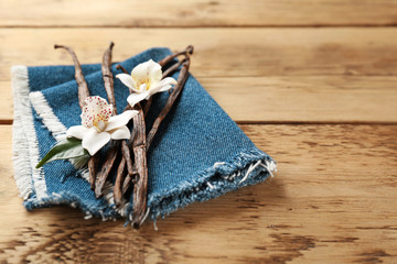 Dried vanilla pods and flowers on wooden background