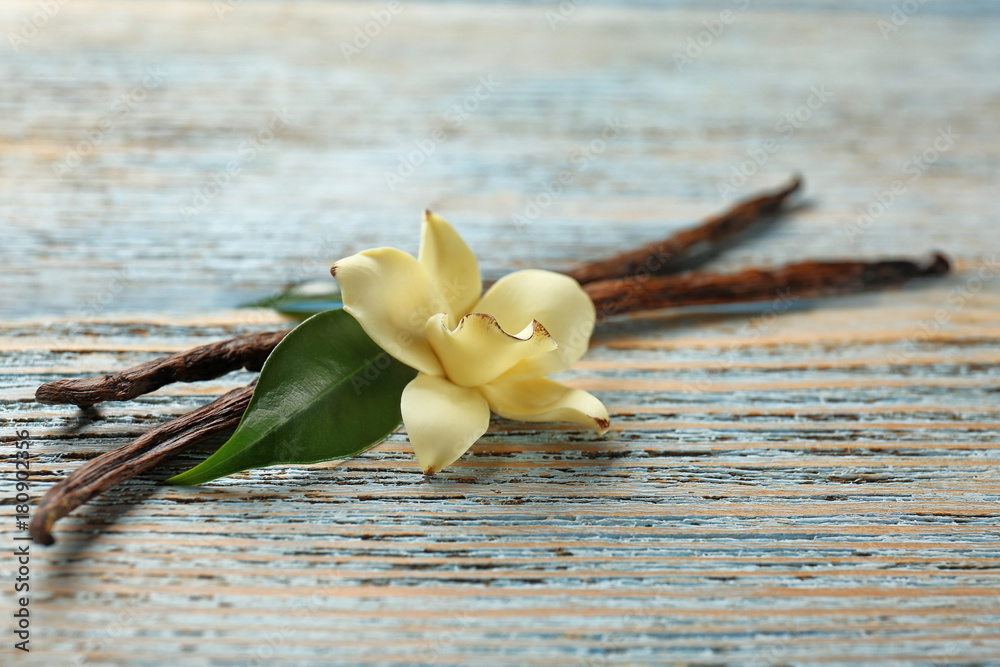 Sticker dried vanilla pods and flower on wooden background