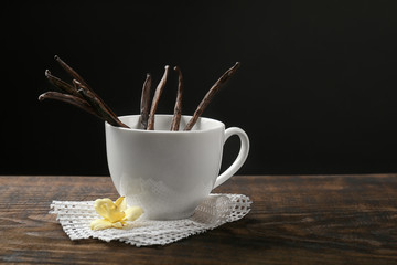 Dried vanilla pods in cup on black background