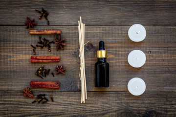 Skin care and relax. Cosmetics and aromatherapy concept. Cinnamon oil and candles on dark wooden background top view