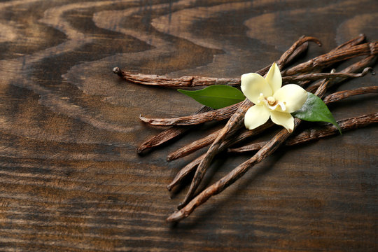 Fototapeta Dried vanilla pods and flower on wooden background
