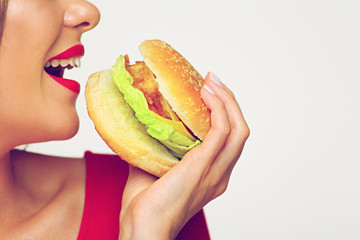 Close up face woman bites burger.