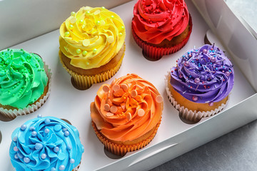 Box with tasty cupcakes on table