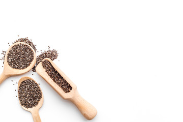 Superfood chia seeds in a wooden spoon and scoop on white background top view copyspace