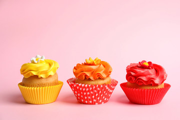 Tasty colorful cupcakes on color background