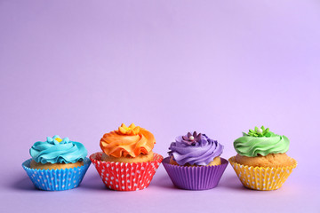 Tasty colorful cupcakes on color background