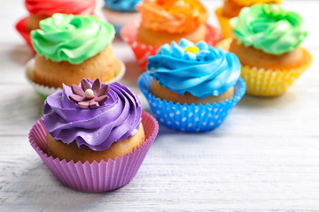 Tasty colorful cupcakes on wooden table