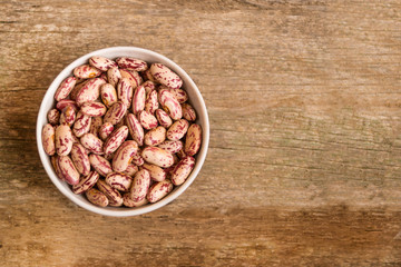 Сolorful kidney beans in the bowl on a wooden table