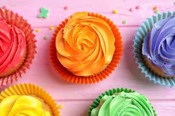 Tasty colorful cupcakes on wooden table