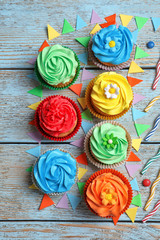 Tasty colorful cupcakes on wooden table