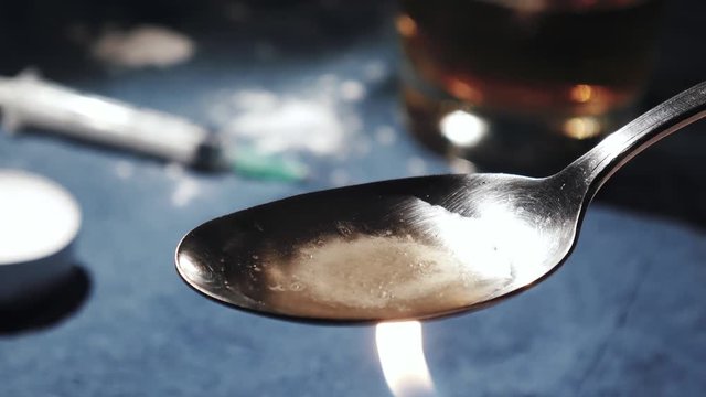 Close up of man cooking white heroin on spoon
