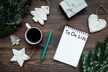 Planning new year. Notebook with to do list near christmas toys, spruce branch and pinecones on wooden background top view