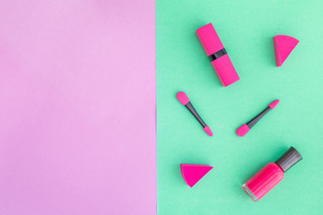 Cosmetics on colorful background. Pink nail polish and lipstick on pink and mint background top view copyspace