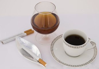 Copa, café y cigarrillo.
Coñac junto al café con un cenicero y un cigarrillo.
