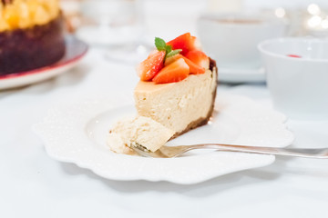 Cheesecake with strawberries and mint leaves on a white plate
