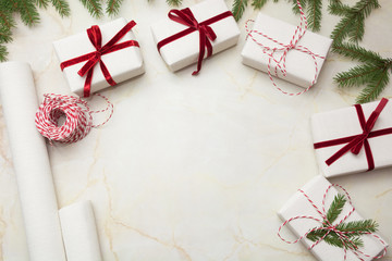 Christmas gift boxes wrapped in white craft paper and decorative red ribbon on marmoreal surface. Flat lay, top view.