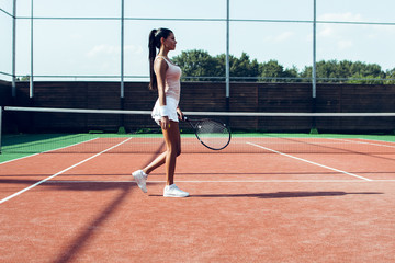 Obraz premium On her way to victory. Side view full length of beautiful young woman standing on the tennis court