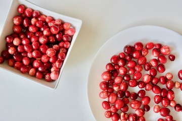 A lot of tasty and healthy red cranberries on the white plates.