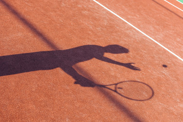  Sunny tennis. Shadow of young man playing tennis on the tennis court.