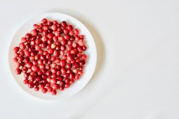 A lot of tasty and healthy red cranberries on the white plate