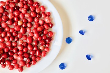 A lot of tasty and healthy red cranberries on the white plate with blue diamonds