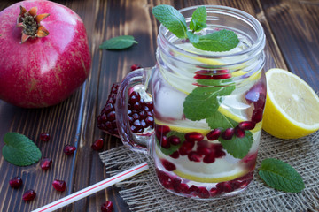 Detox water with pomegranate, lemon and mint on the rustic wooden background