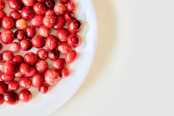 A lot of tasty and healthy red cranberries on the white plate