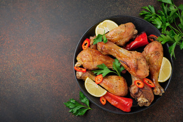 Fried chicken's pointed shanks in a cast-iron frying pan on a dark concrete or stone background. Selective focus.Top view.