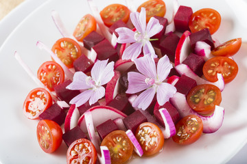 Ensalada de remolacha tomates cherry cebolla morada y rábanos con aceite de oliva decorada con flor de malva