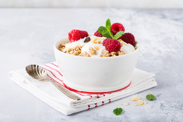 Oat granola with berries and yoghurt on light gray background. Copy space. Healthy breakfast concept.