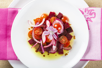 Ensalada de remolacha tomates cherry cebolla morada y rábanos con aceite de oliva decorada con flor de malva