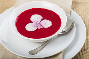 Sopa fría o gazpacho de remolacha rábano cebolla morada y tomate para una comida sana o vegetariana decorada con flor de malva