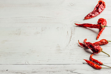 Dried red chili peppers over light wooden background