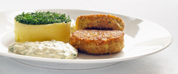a portion of pike cutlets with potato decorated with dill and tartar sauce