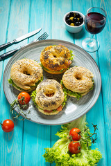 Bagels with salmon, vegetables, cream-cheese and glass of red wine on blue wood background