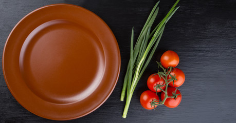 Brown clay dish and tomatoess on black background