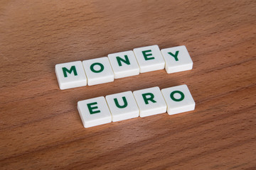 Money Euro Word with Green Letters on Wooden Background