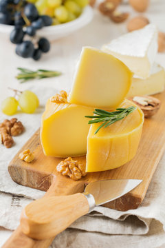 Stack Camembert cheese with grapes, walnuts and basil on gray light concrete or stone background. Selective focus.