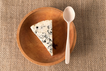 white cheese with mold in an old wooden bowl with a wooden spoon stands on a linen cloth