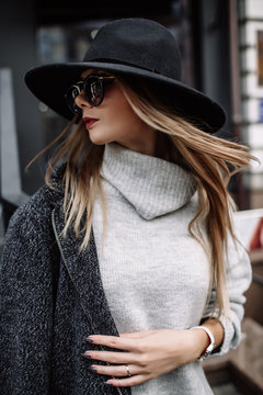 portrait of a young beautiful fashionable woman wearing sunglasses. A model in a stylish wide-brimmed hat. Harmoniously similar clothes in gray tones. Uleach style of shooting. Women's fashion.